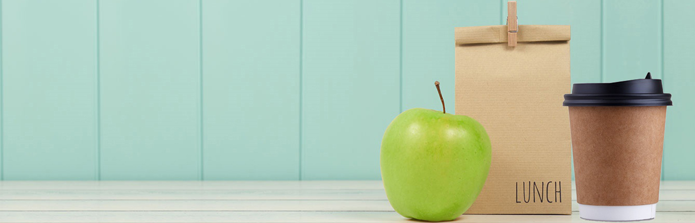 A brown lunch bag with a green apple and takeaway cup of coffee.